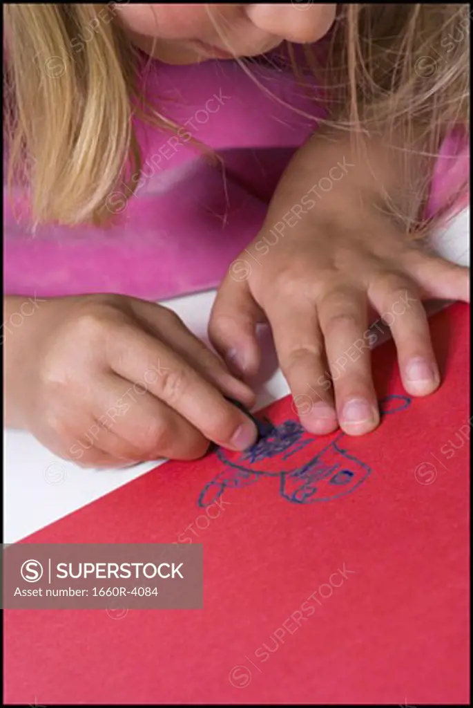 High angle view of a girl drawing on construction paper