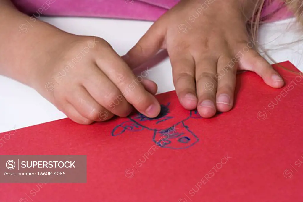 High angle view of a girl drawing on a chart using crayons