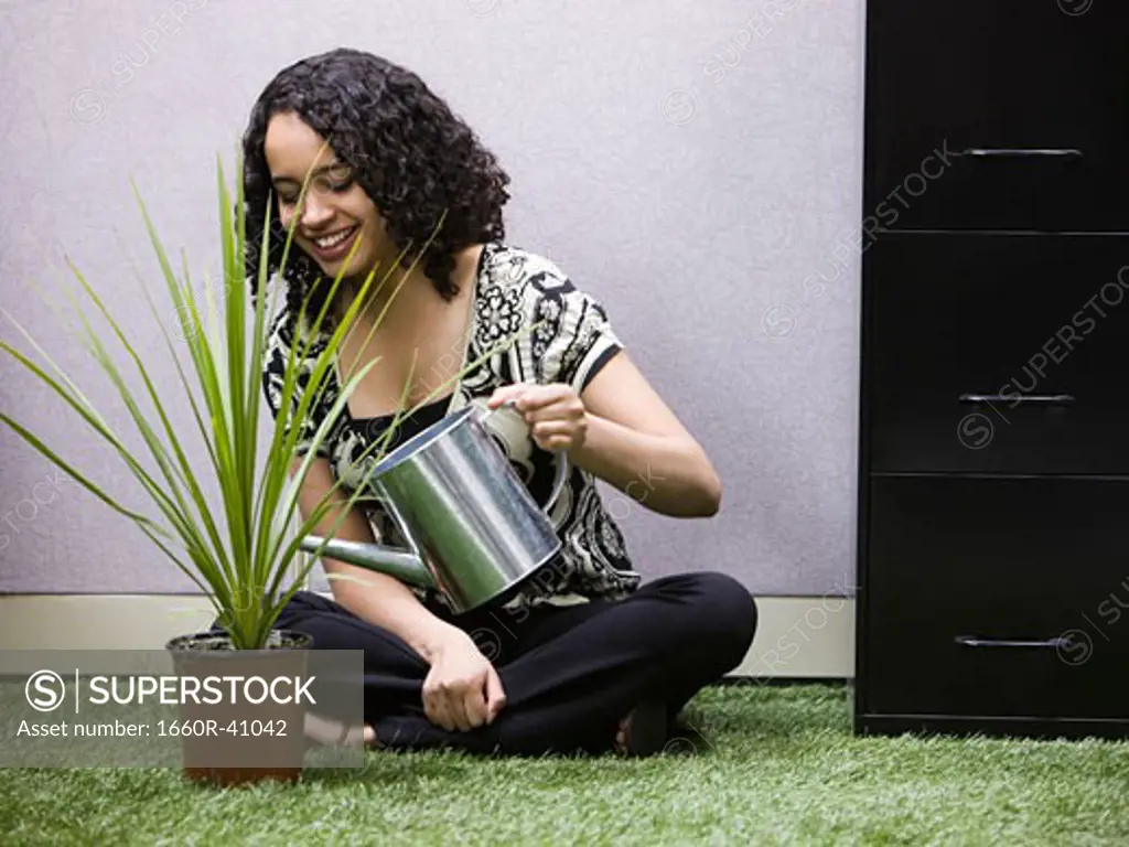 woman watering a plant in her "green" office