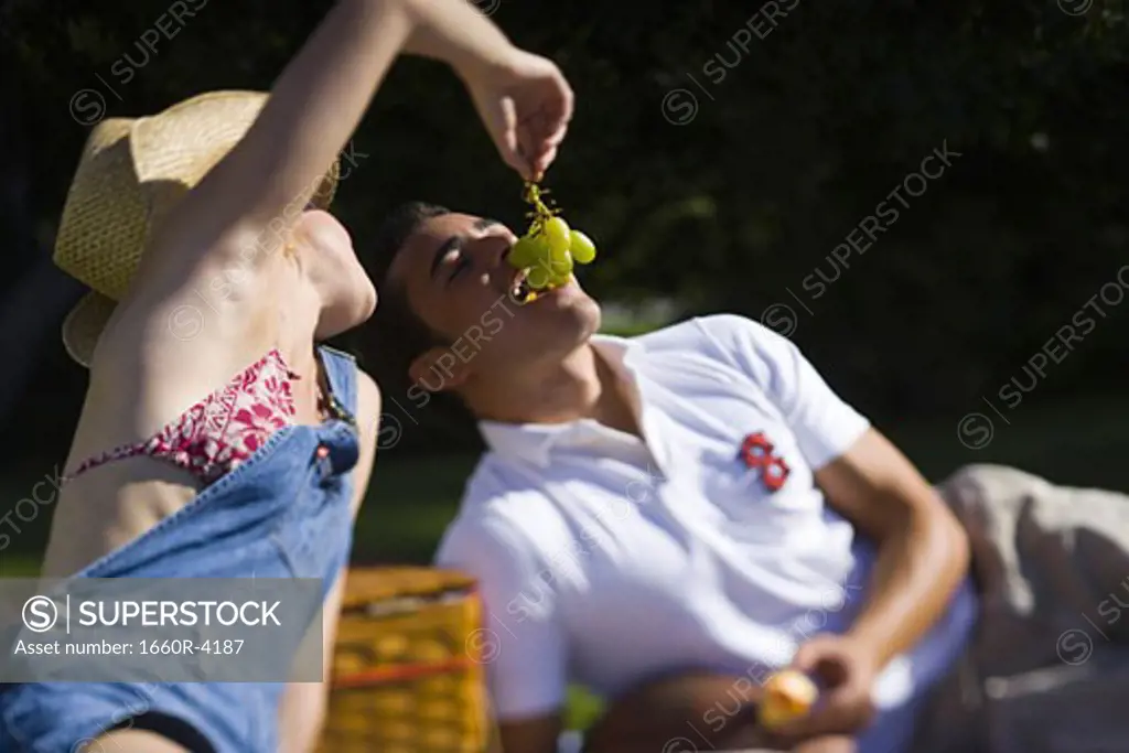 Close-up of a young woman feeding grapes to a young man