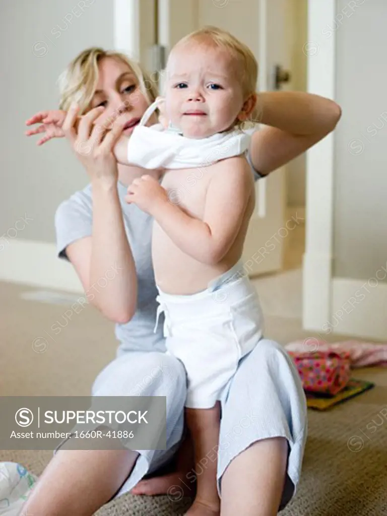 mother putting clothes on baby girl