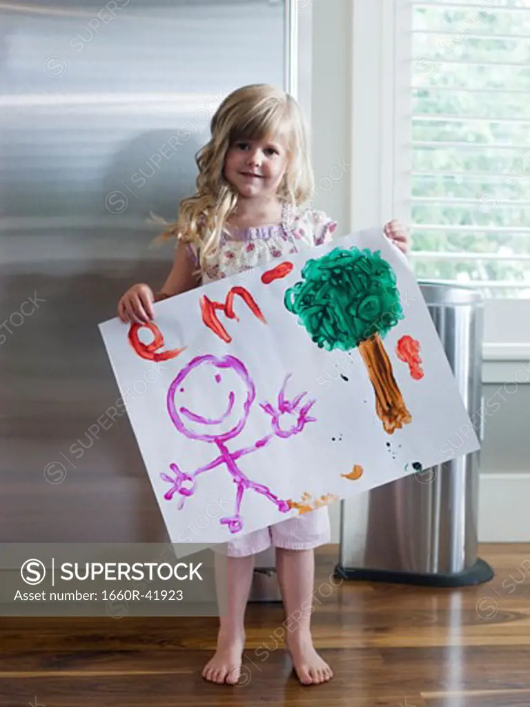 little girl holding up a drawing