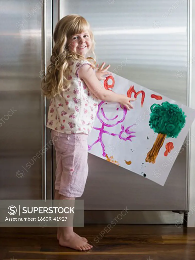 little girl holding up a drawing