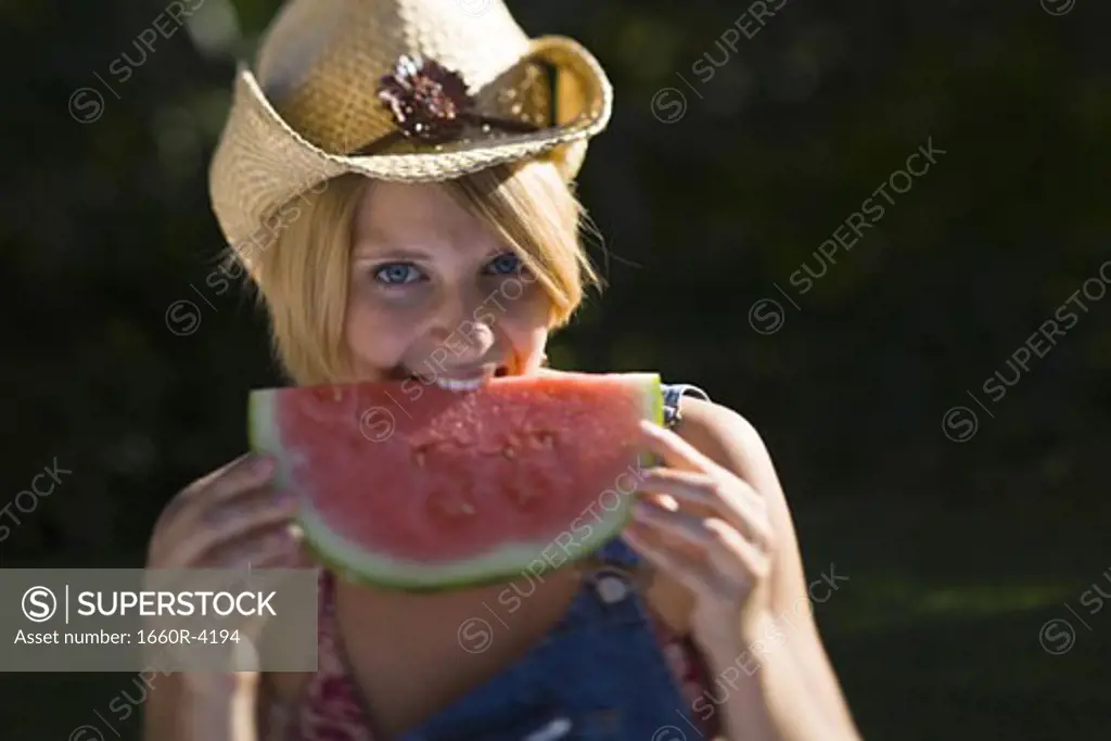 Portrait of a young woman biting a piece of watermelon