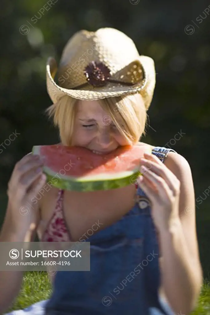 Young woman biting a piece of a watermelon