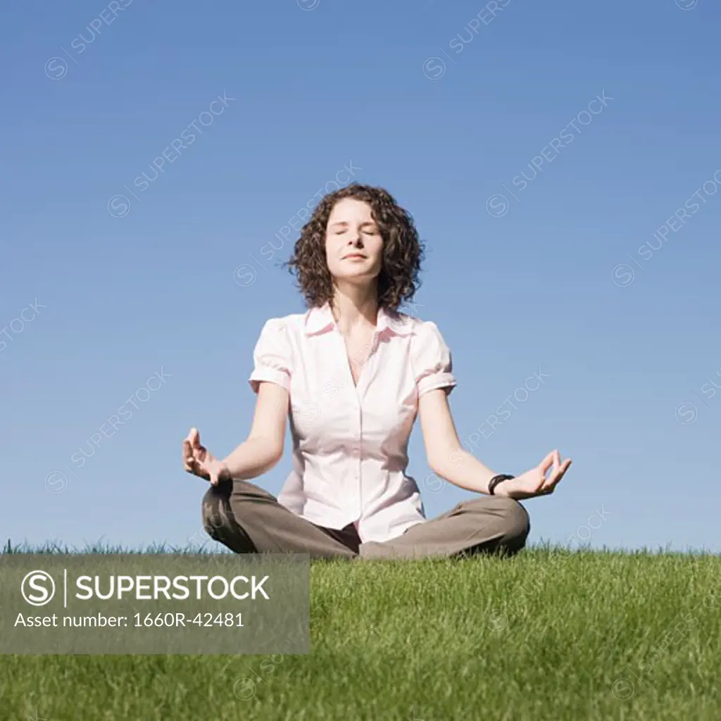 businesswoman meditating on the grass