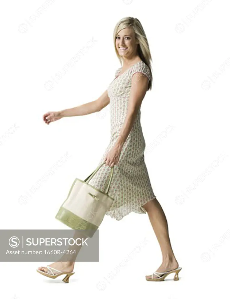 Portrait of a young woman walking with a purse
