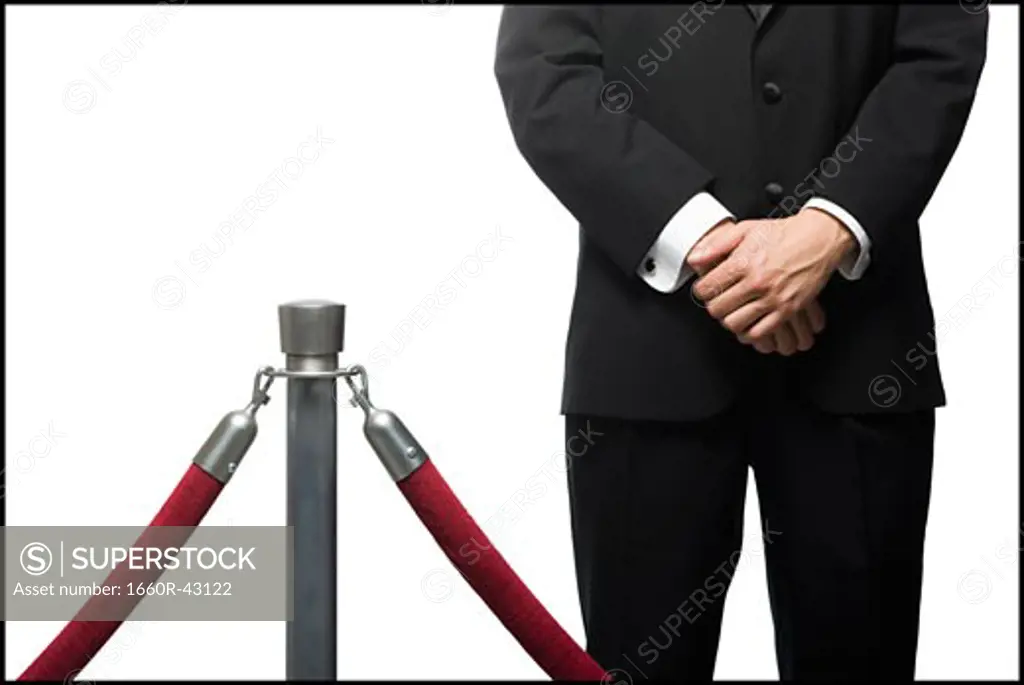 man in a tuxedo next to a velvet rope
