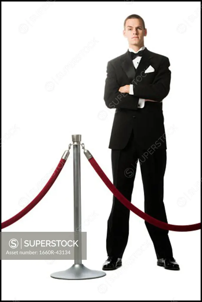 man in a tuxedo next to a velvet rope