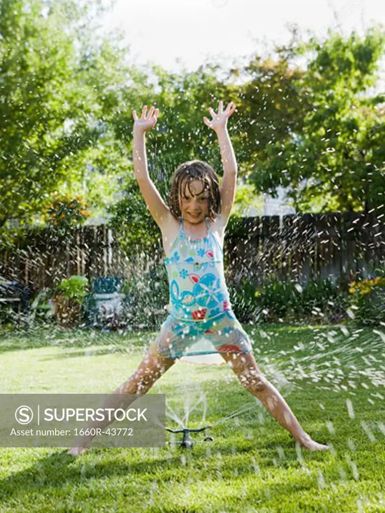girl playing in a sprinkler