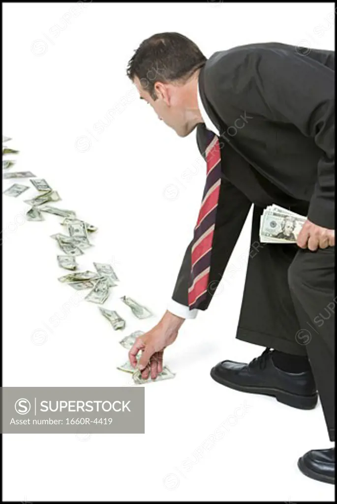 Rear view of a businessman picking up fallen money