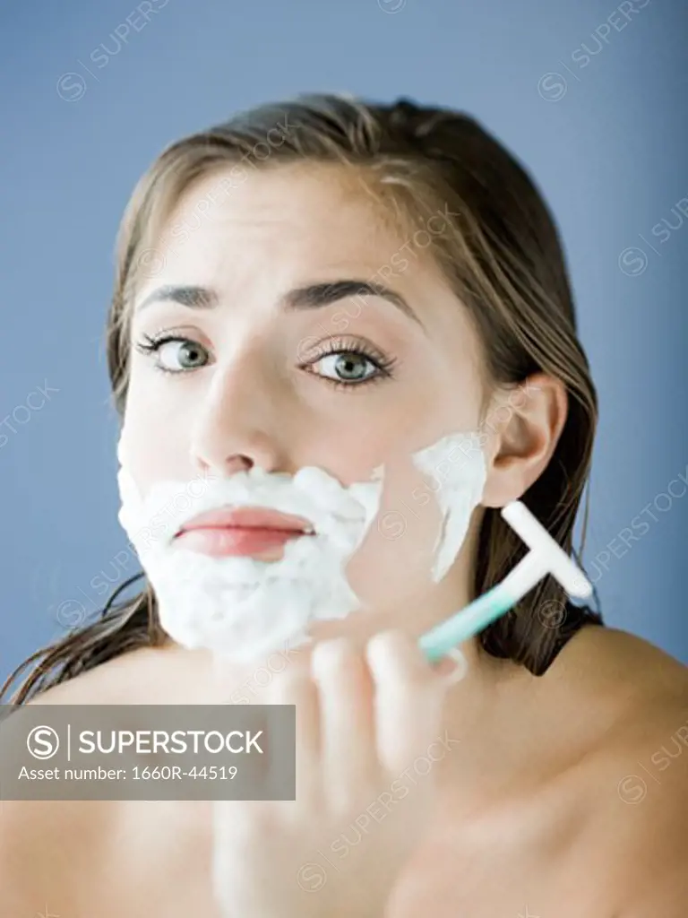 woman shaving her face with a razor and shaving cream