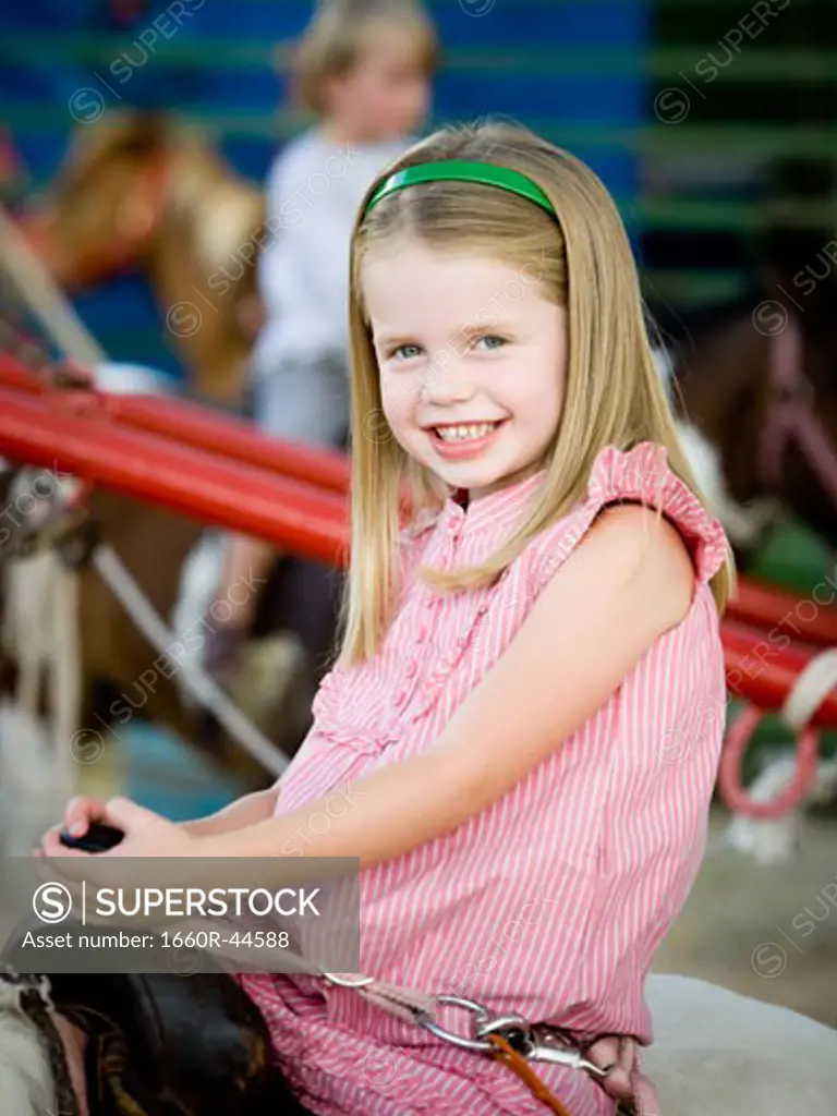 girl sitting on a pony at the carnival