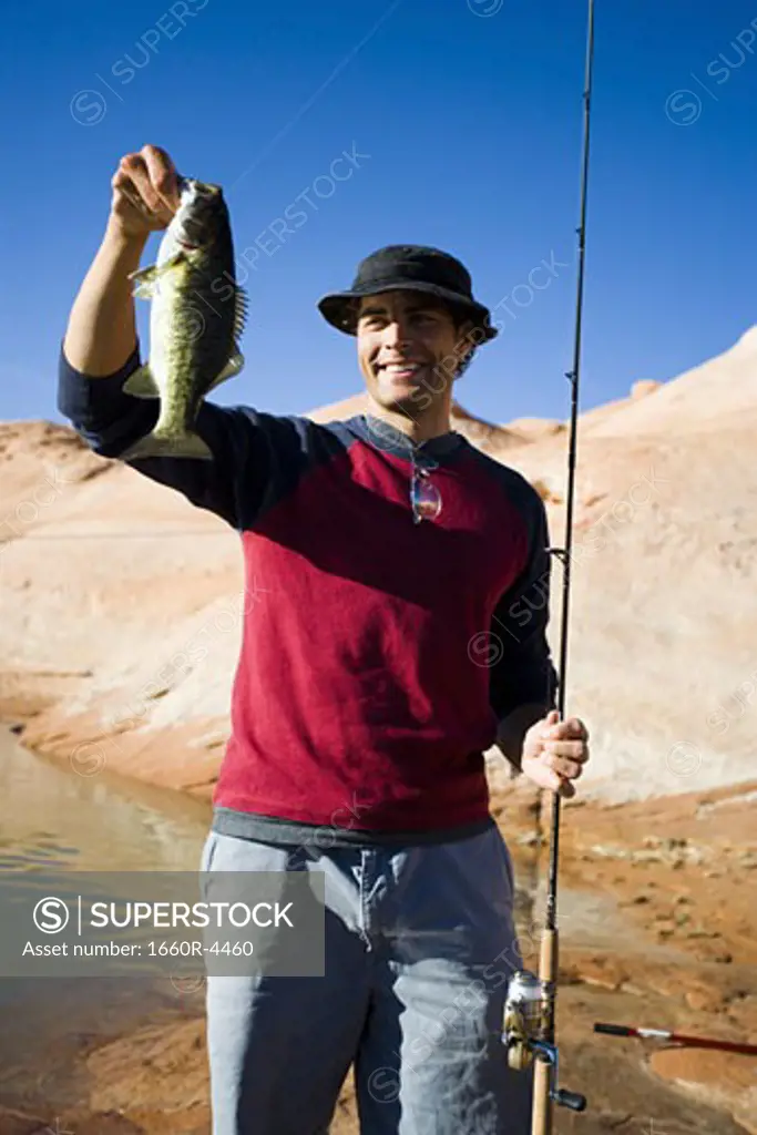 Young man holding a fish with a fishing pole