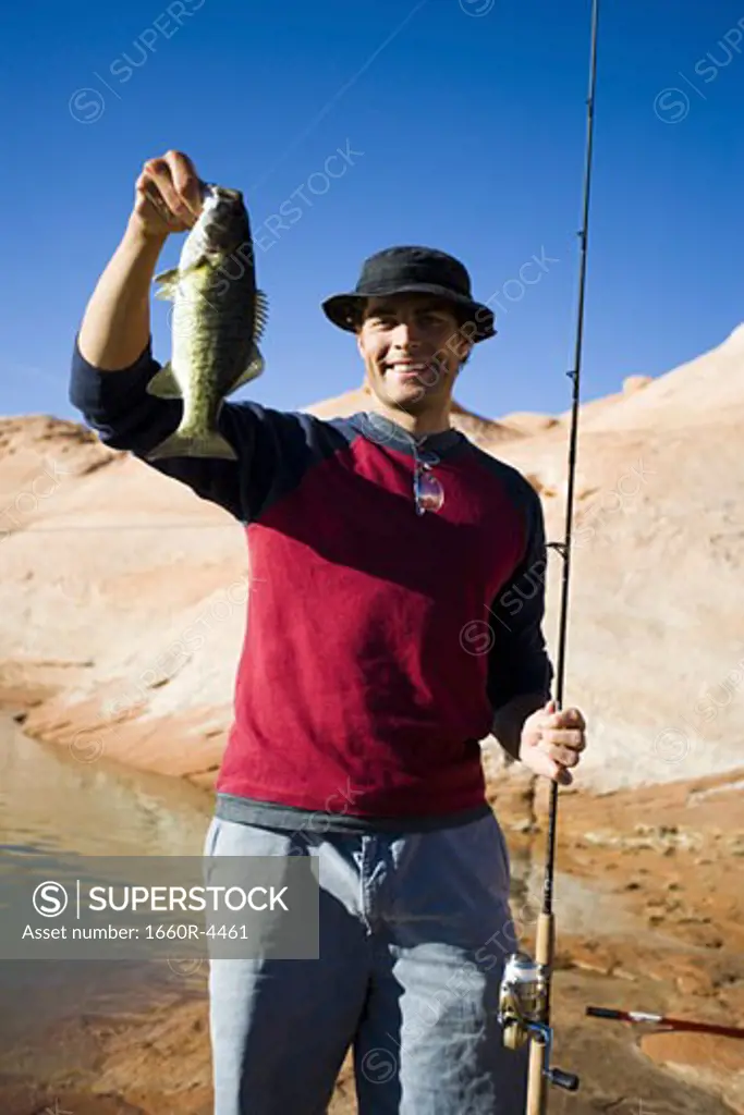 Young man holding a fish with a fishing pole