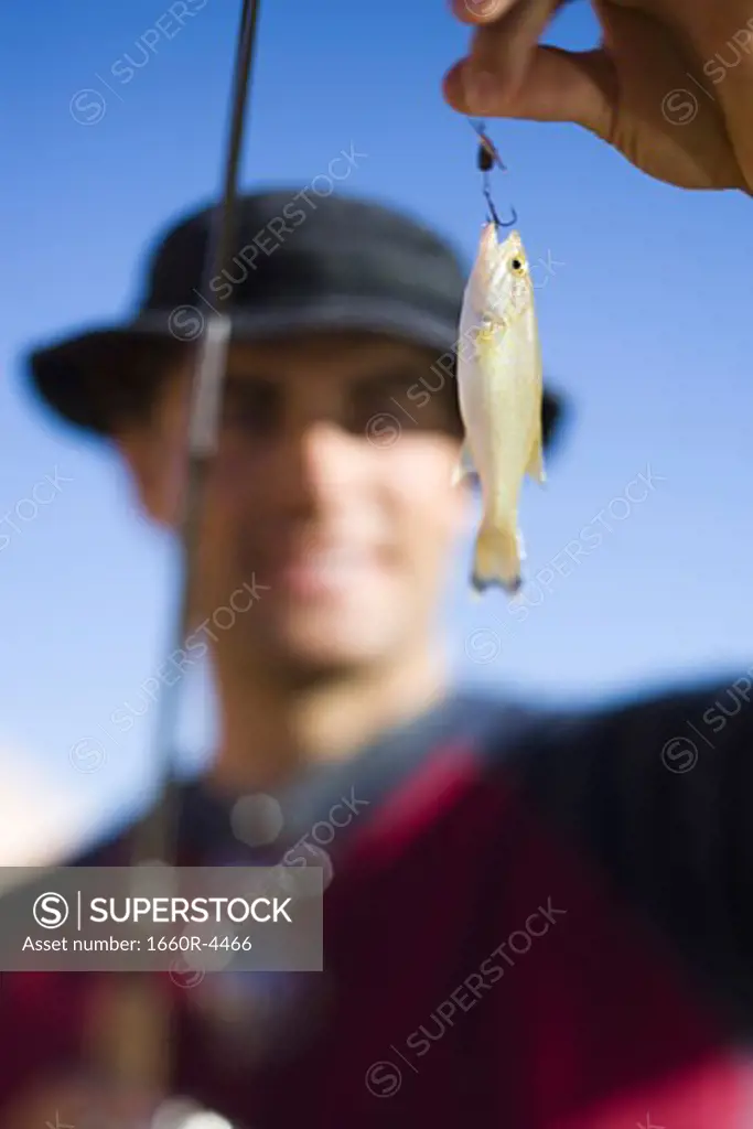 Young man holding a fishing bait with a fishing pole