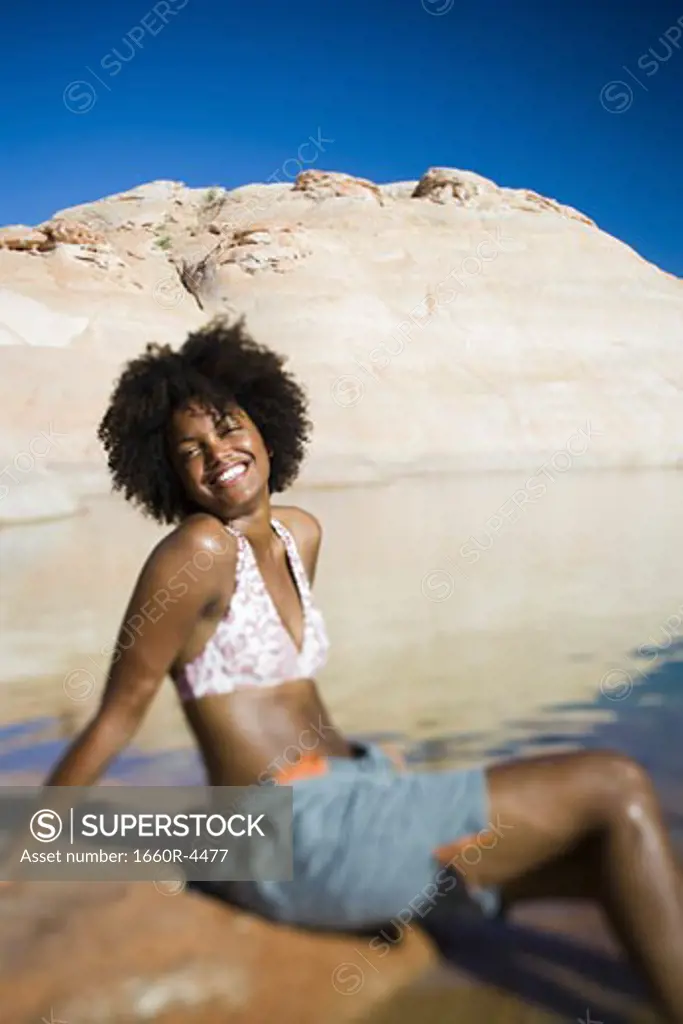 Profile of a young woman sitting on a rock and smiling