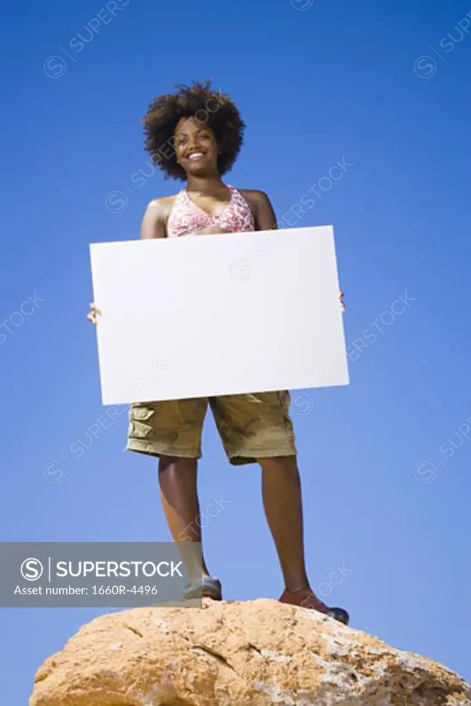 Low angle view of a young woman holding a blank sign