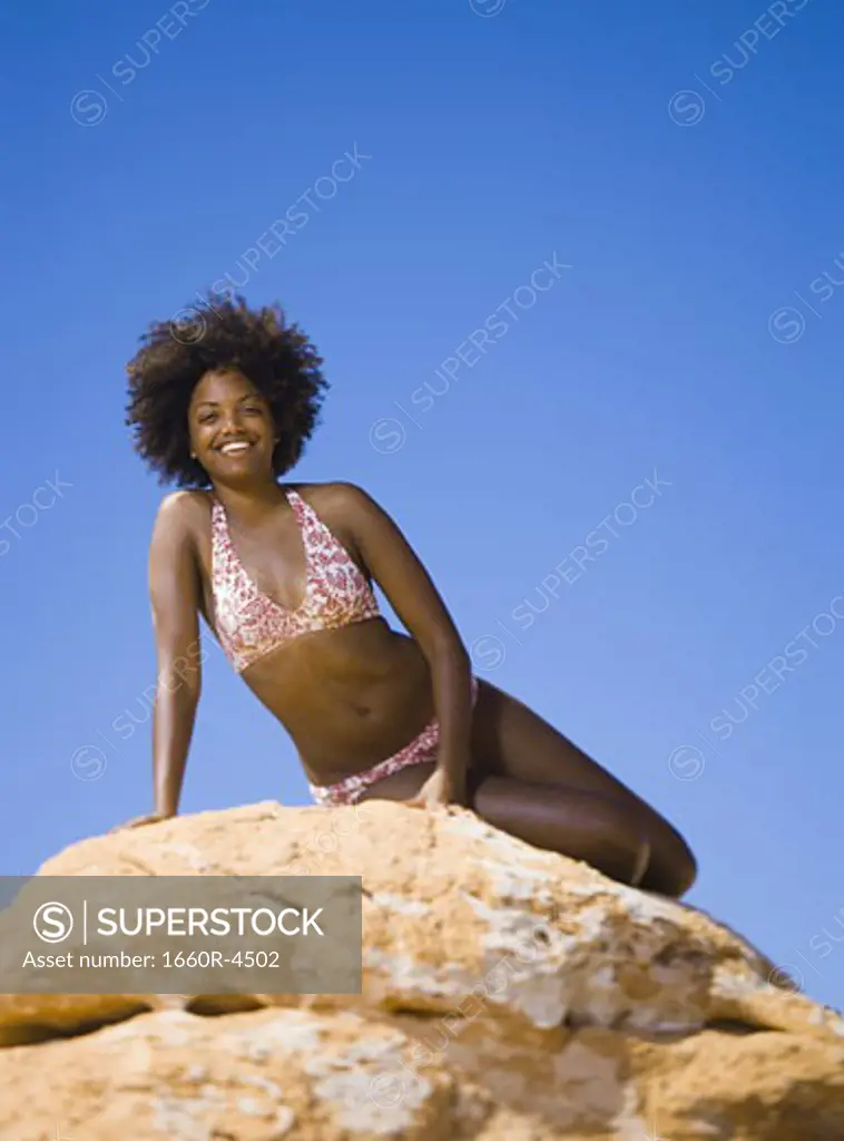 Low angle view of a young woman sitting on a rock