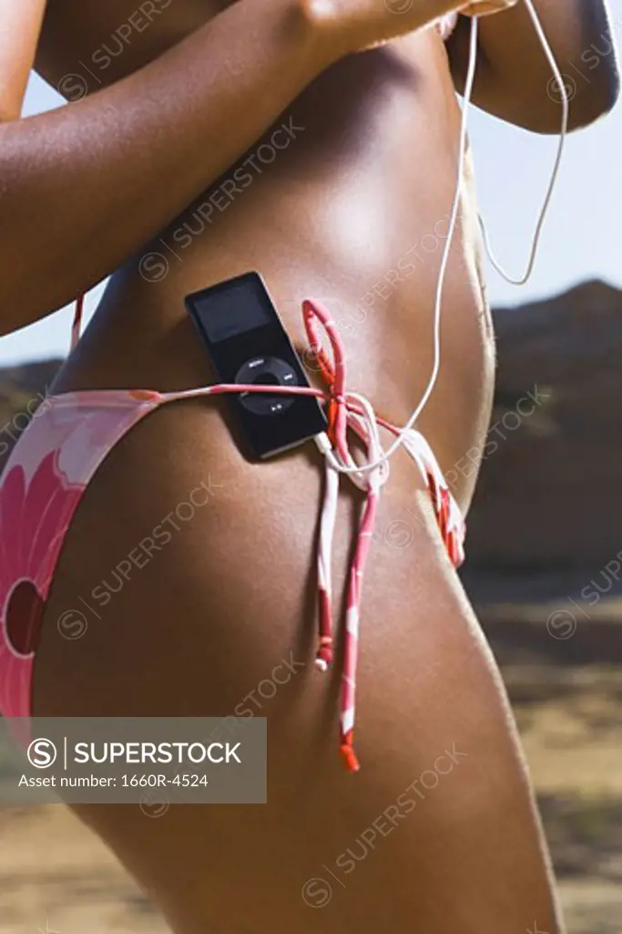Mid section view of a young woman with an MP3 Player on her bikini bottom