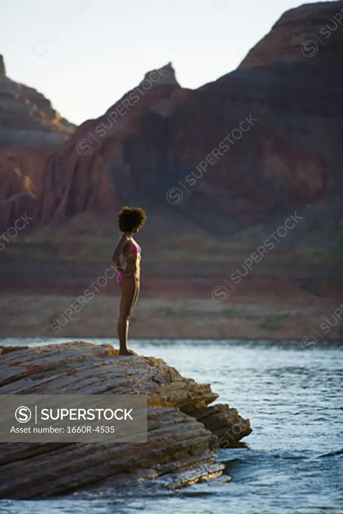 Profile of a young woman standing on a rock
