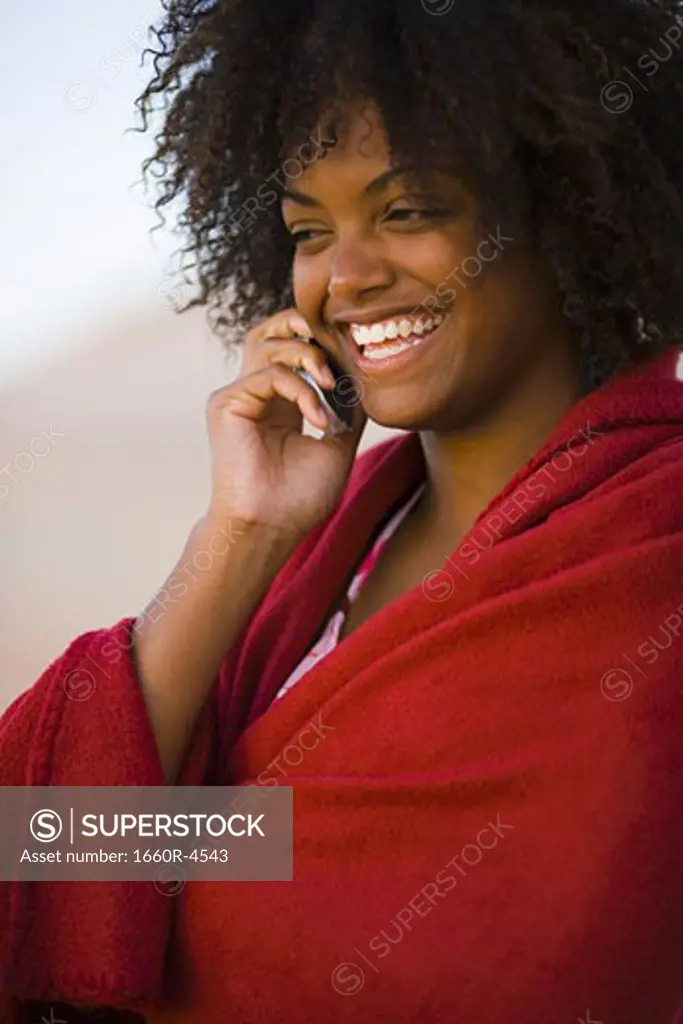 Close-up of a young woman wrapped in a towel talking on a mobile phone