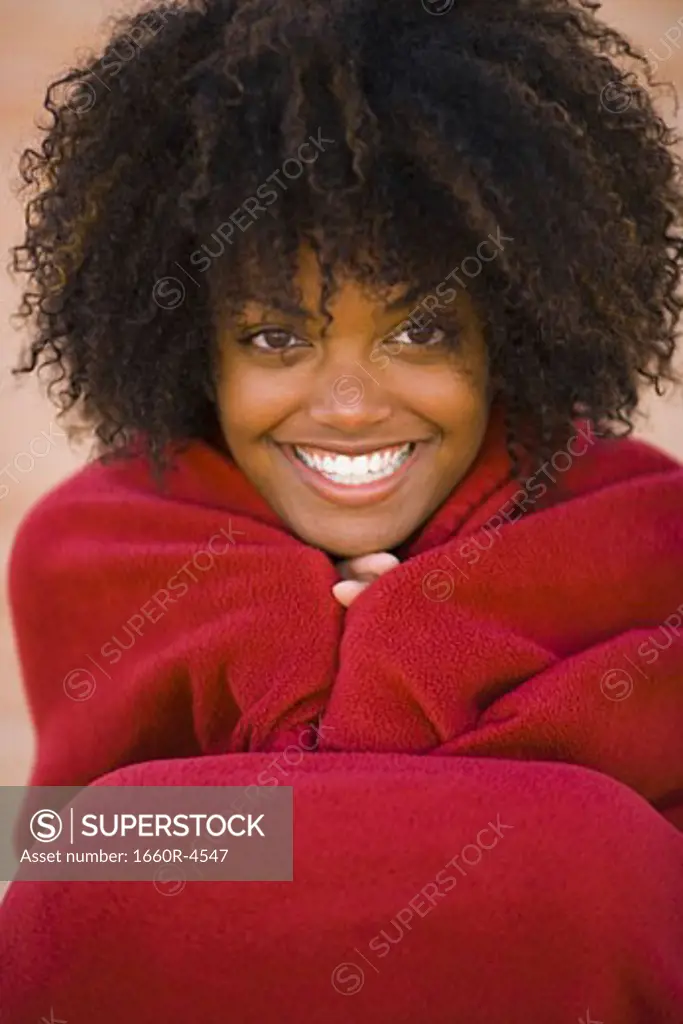 Portrait of a young woman wrapped in a blanket, smiling