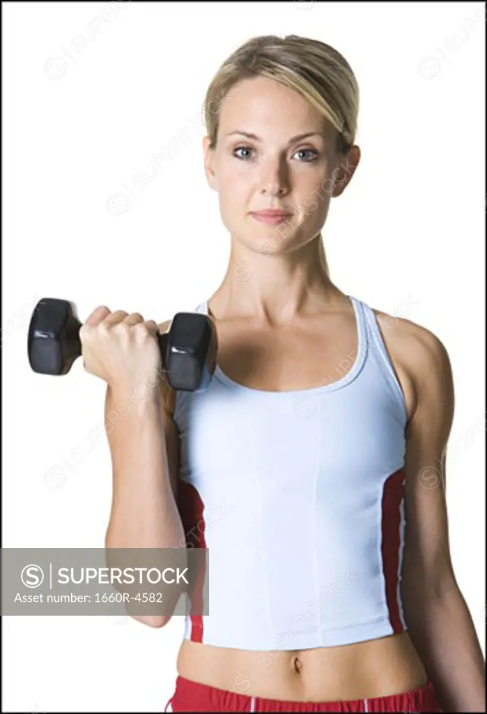 Portrait of a young woman picking up a dumbbell