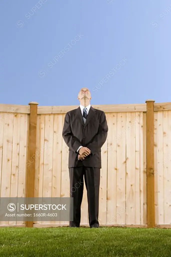 Low angle view of a businessman standing in front of a wall looking up