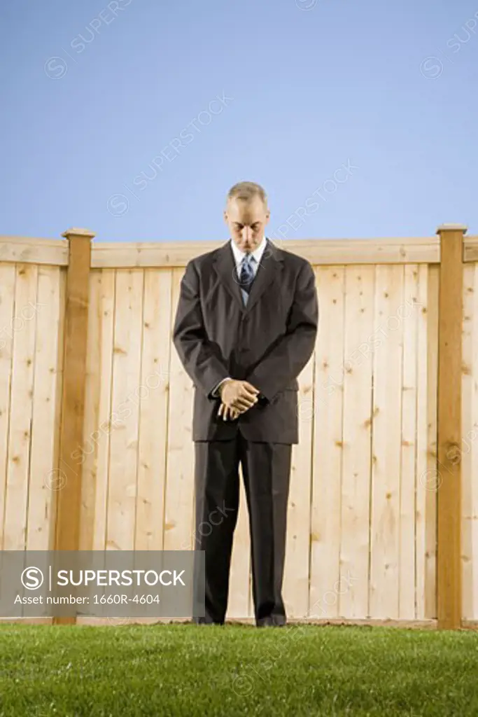 Low angle view of a businessman standing in front of a wall looking down