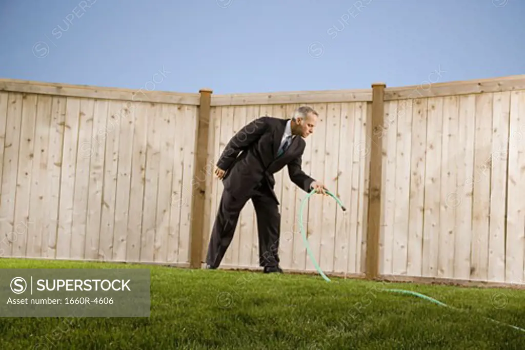 Low angle view of a businessman watering with a hose