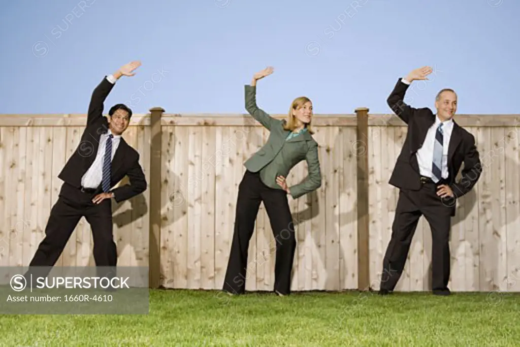 Low angle view of two businessmen and a businesswoman exercising