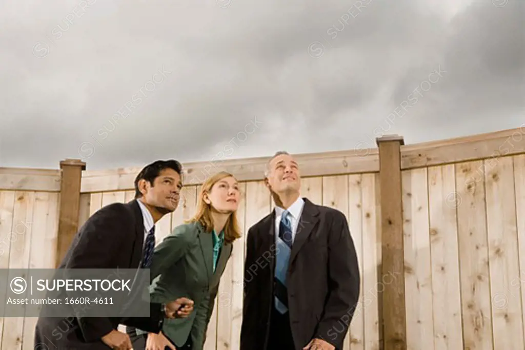 Low angle view of two businessmen and a businesswoman standing looking up