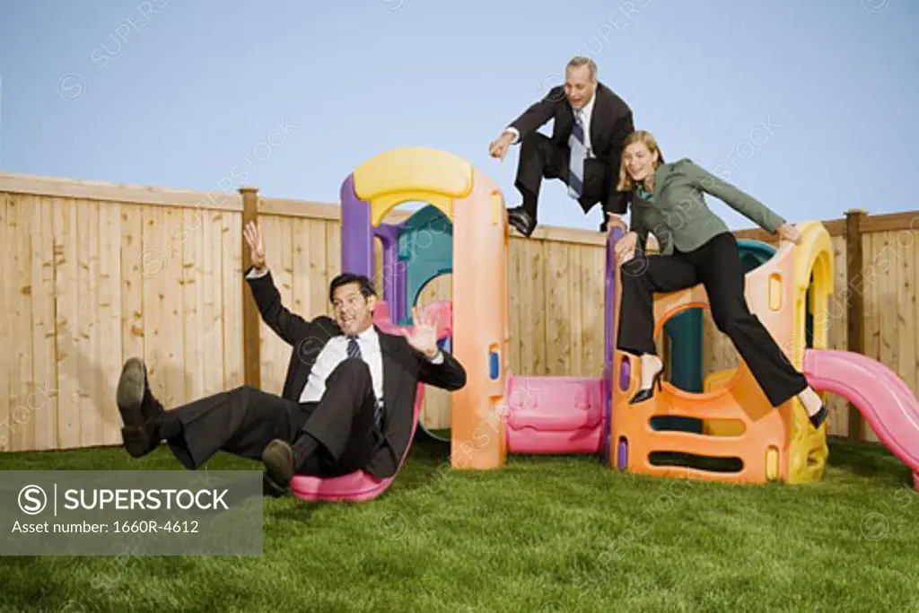 Two businessmen and a businesswoman playing with jungle gym