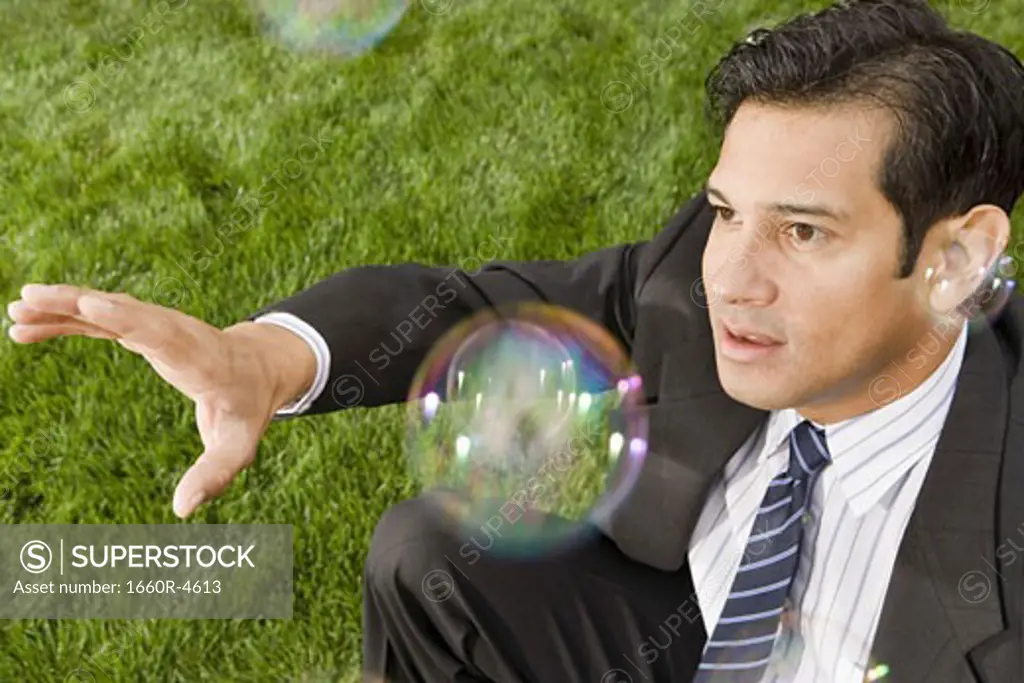 High angle view of a businessman reaching for a soap bubble