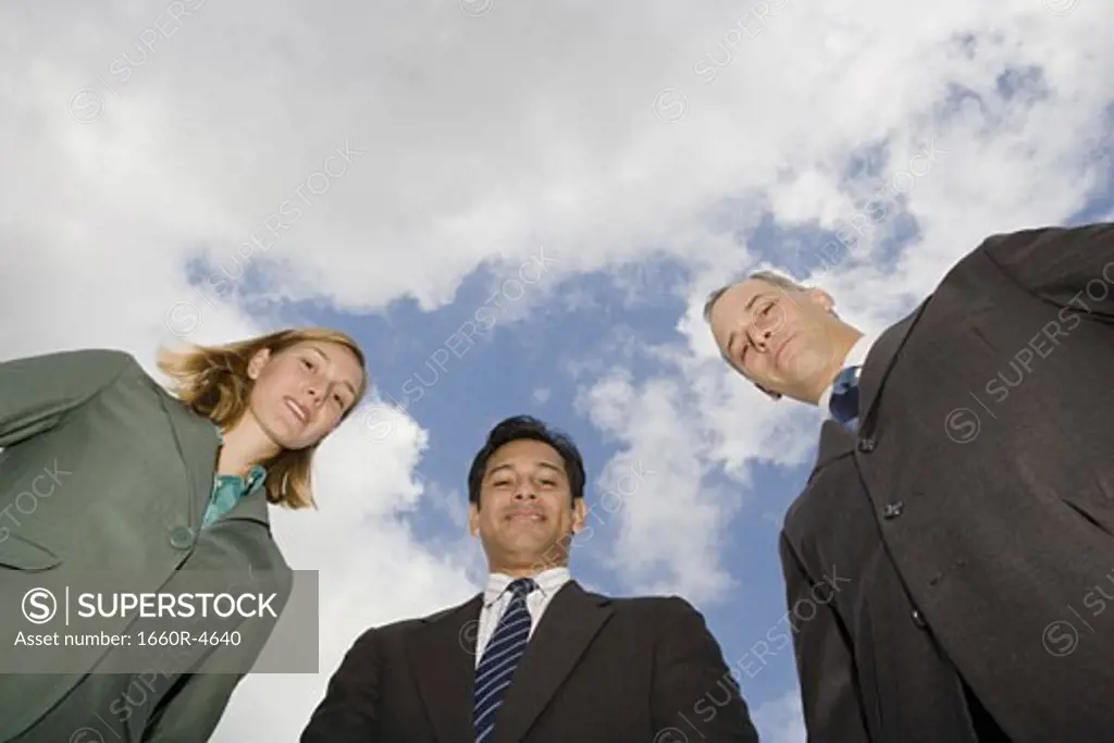 Low angle view of two businessmen and a businesswoman standing