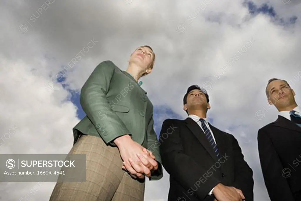 Low angle view of two businessmen and a businesswoman standing