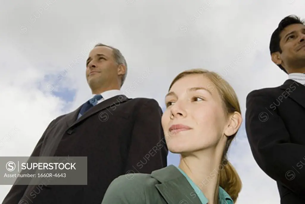 Low angle view of two businessmen and a businesswoman smiling