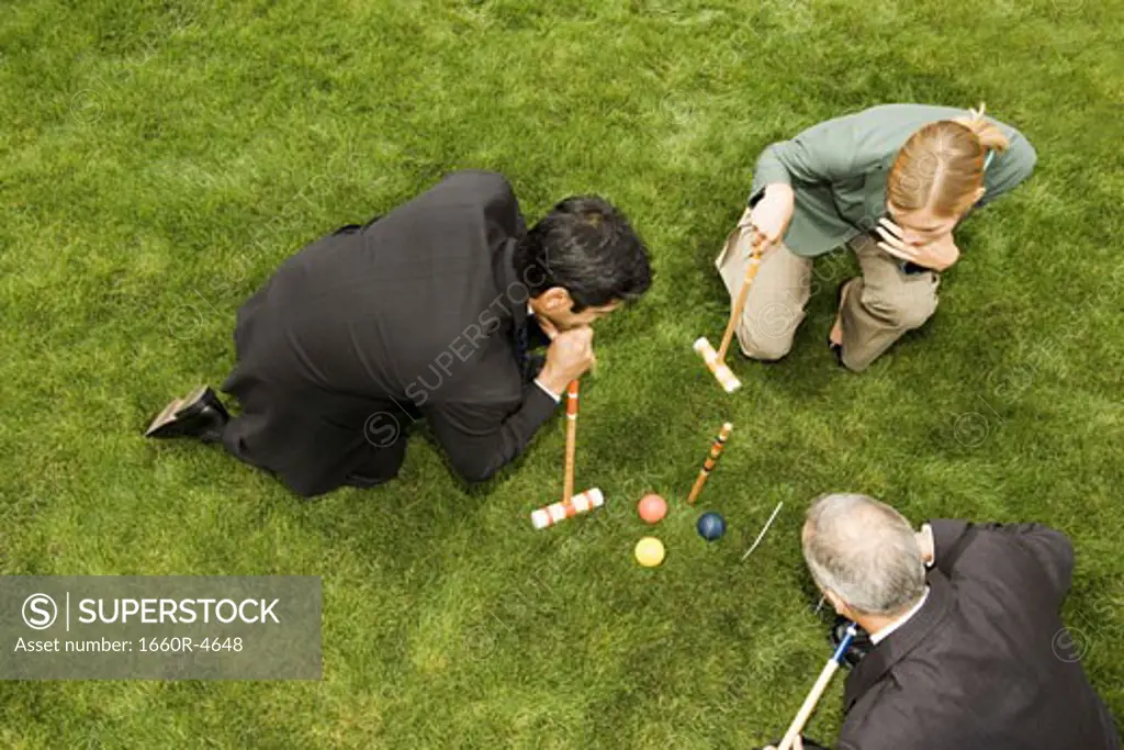 High angle view of two businessmen and a businesswoman playing croquet