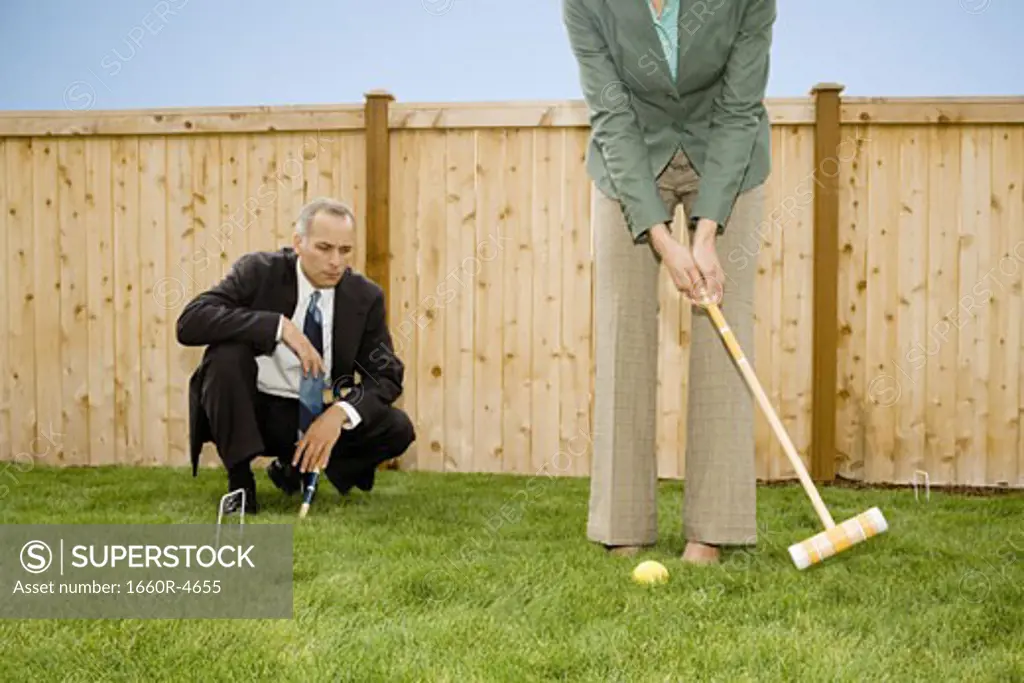 Businessman and a businesswoman playing croquet