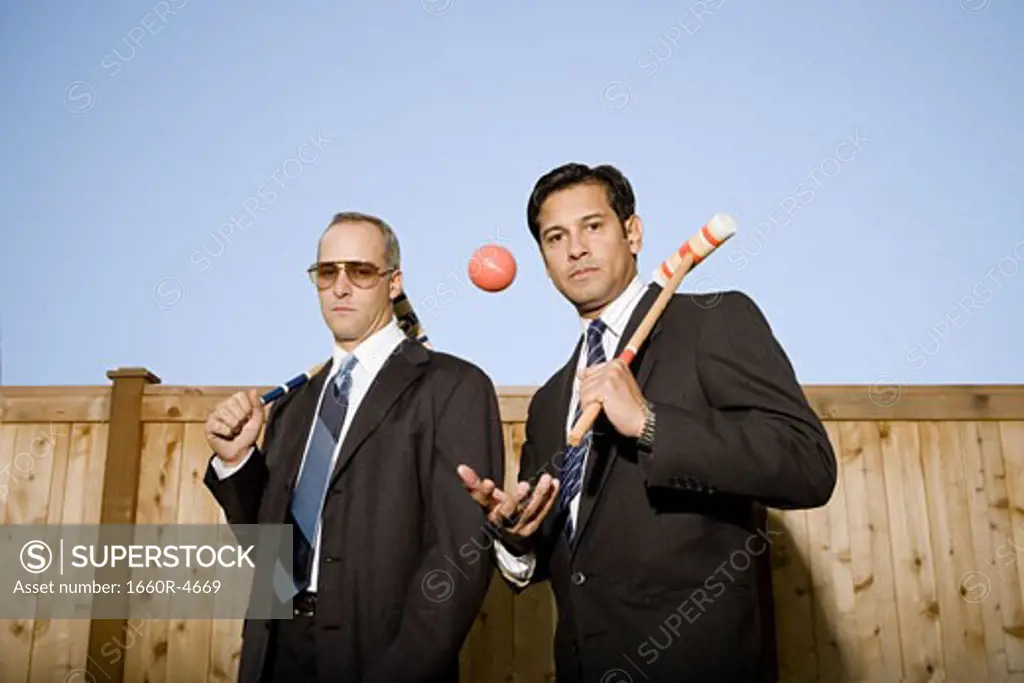 Portrait of two businessmen carrying a croquet mallet