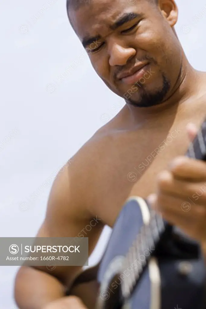 Close-up of a young man playing a guitar