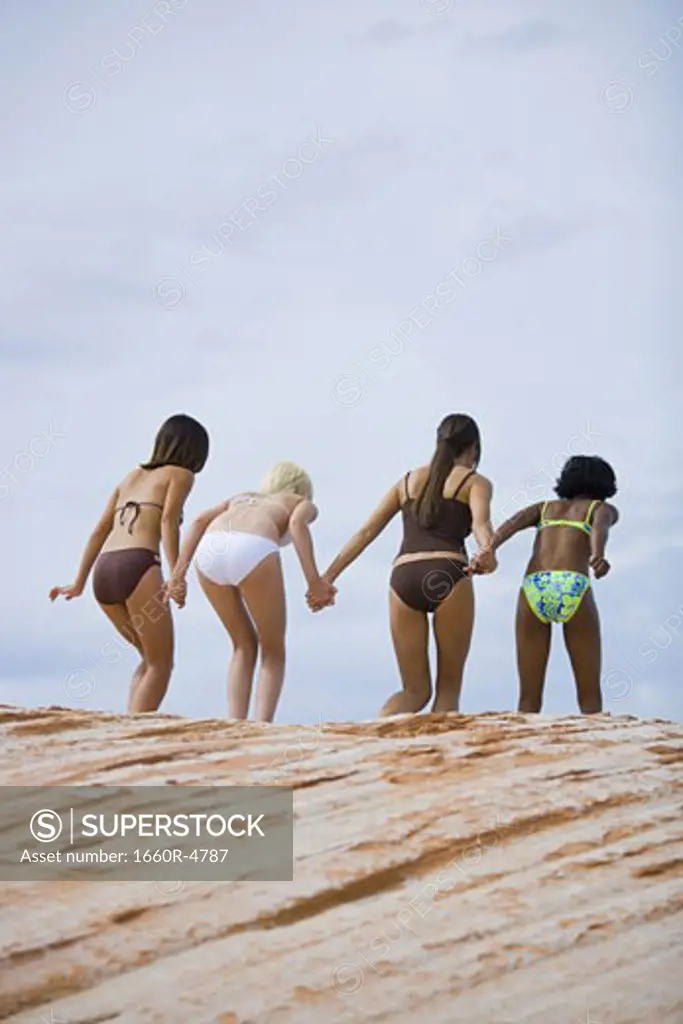 Rear view of four young women jumping