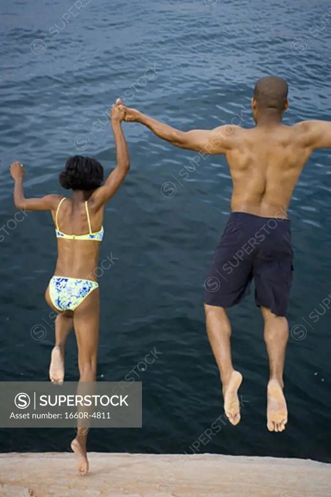 High angle view of a young couple jumping into a lake