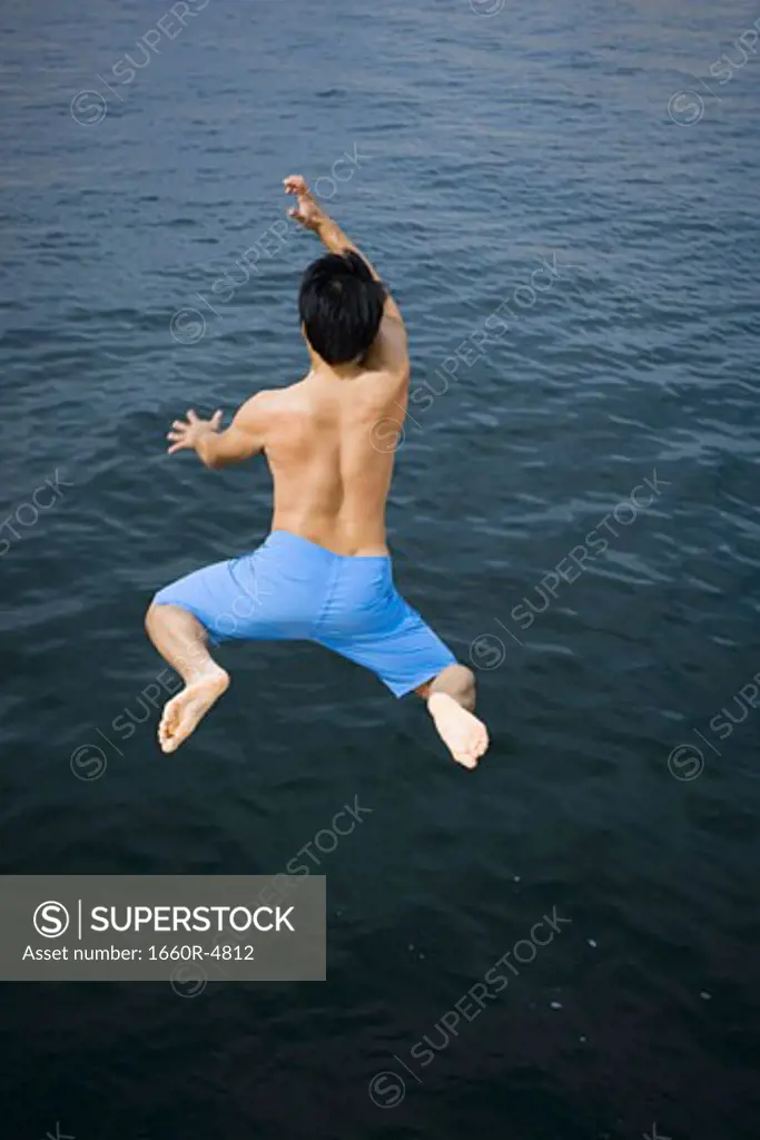 Rear view of a young man jumping in a lake