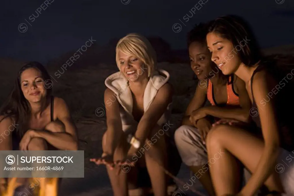 Four young women sitting at a campfire