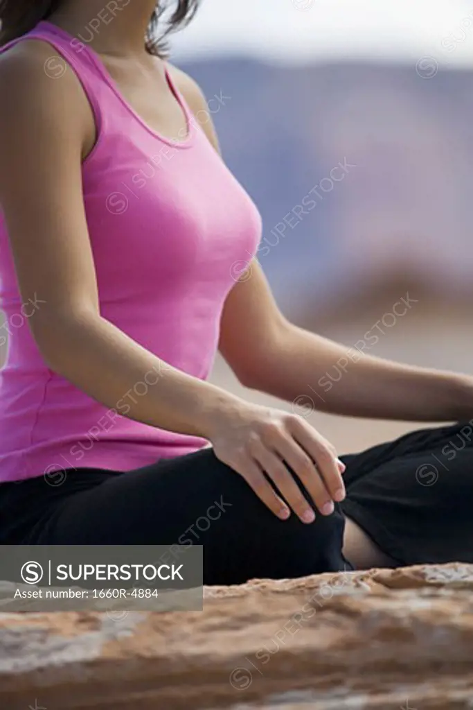 Mid section view of a young woman meditating