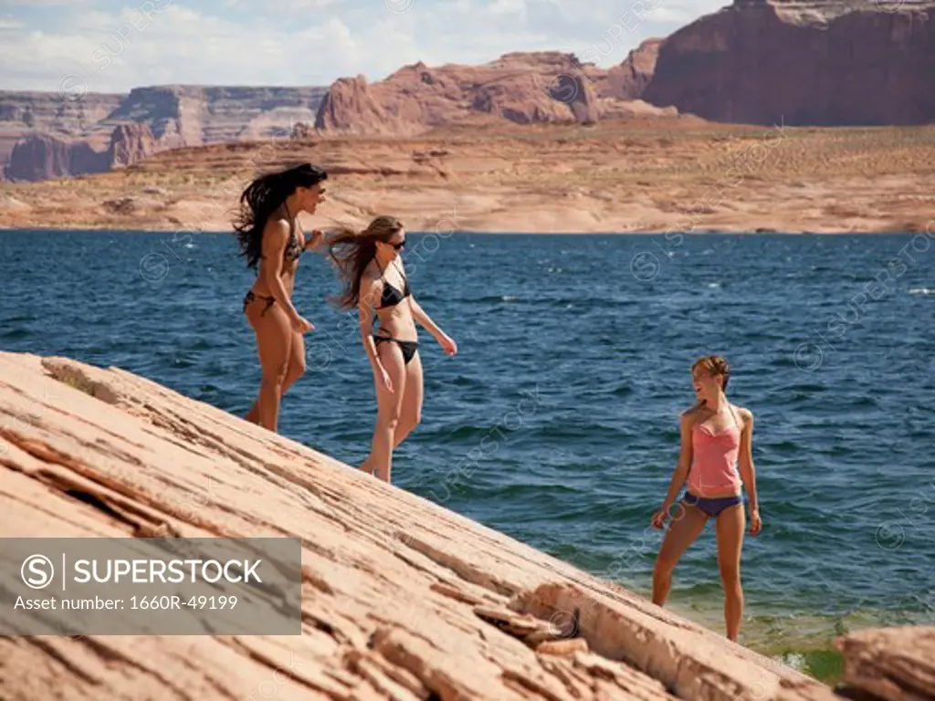 USA, Utah, Lake Powell, Three young women in bikini on lakeshore
