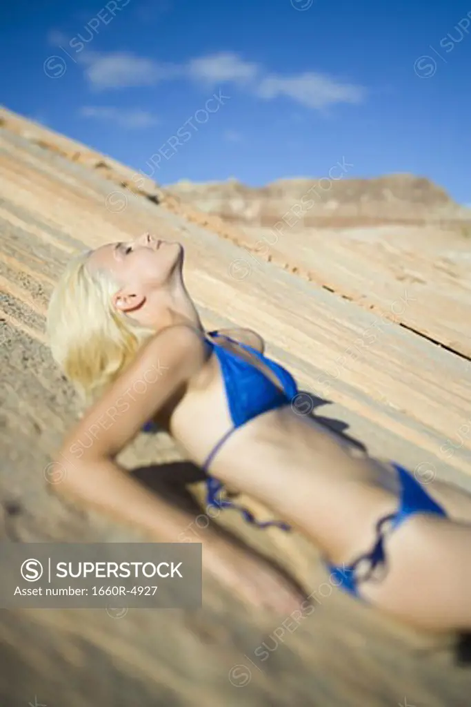Profile of a young woman lying on a rock
