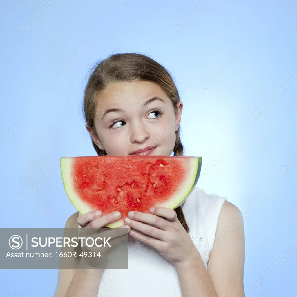 Studio shot of girl (10-11) holding slice of watermelon